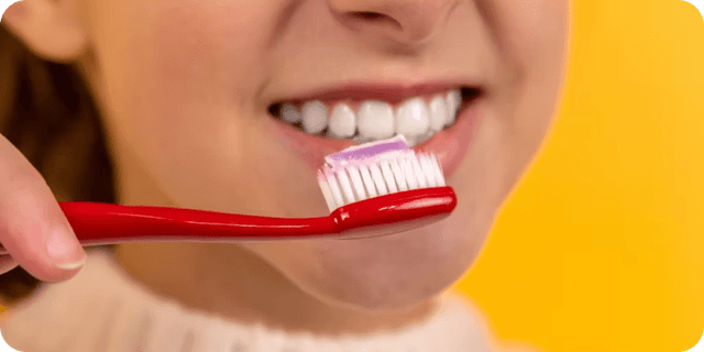 A picture of a girl brushing her teeth. The picture has a yellow background